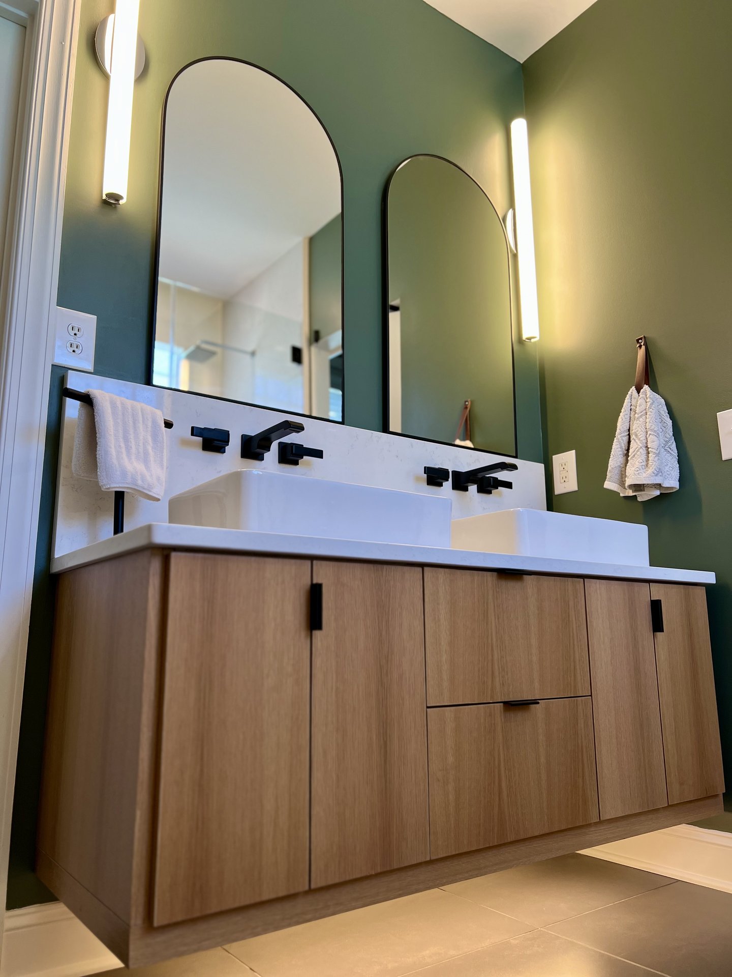 Modern floating oak vanity with sage green walls by Hatley Construction