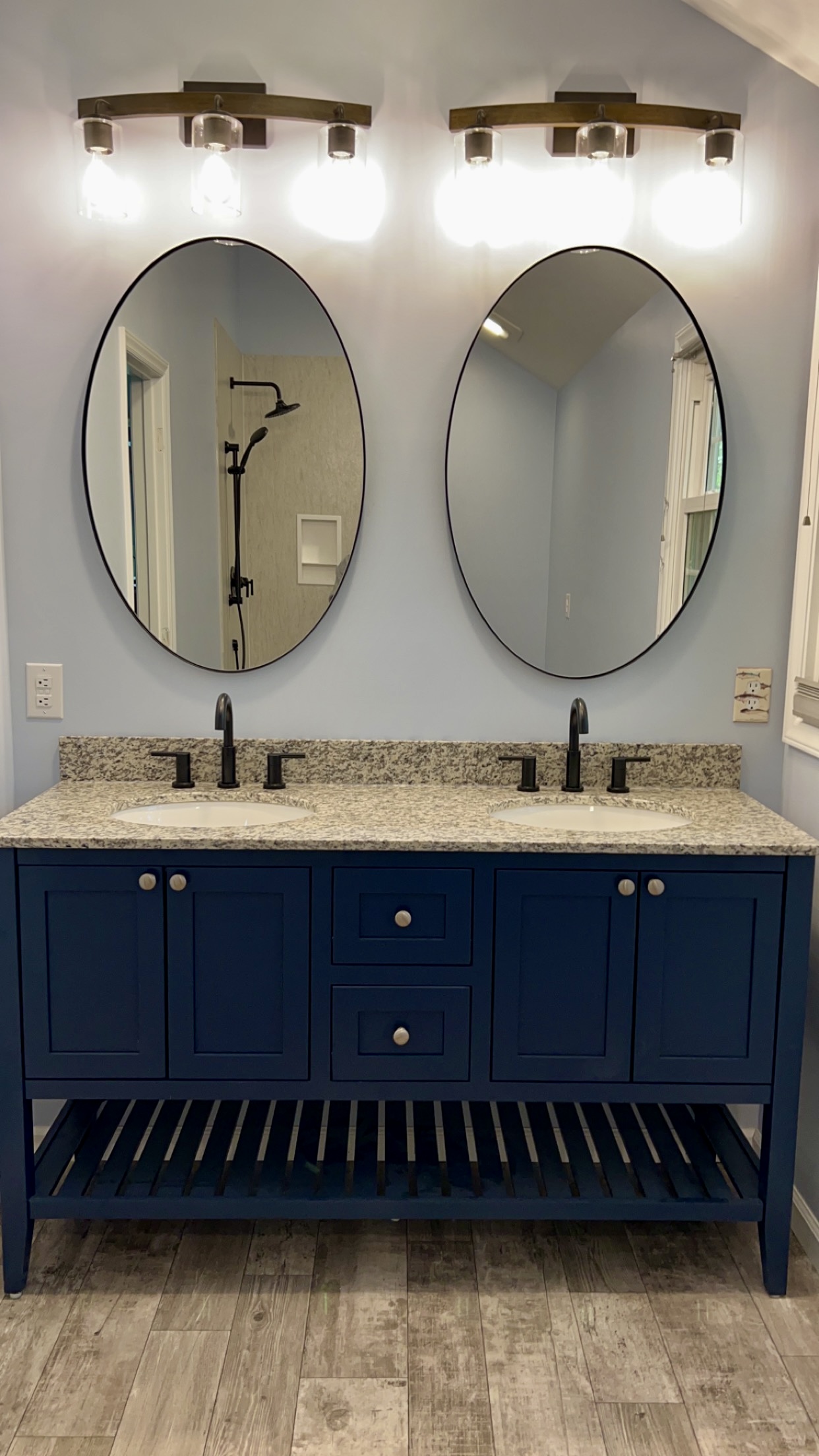 Navy bath vanity with oval mirrors and granite top